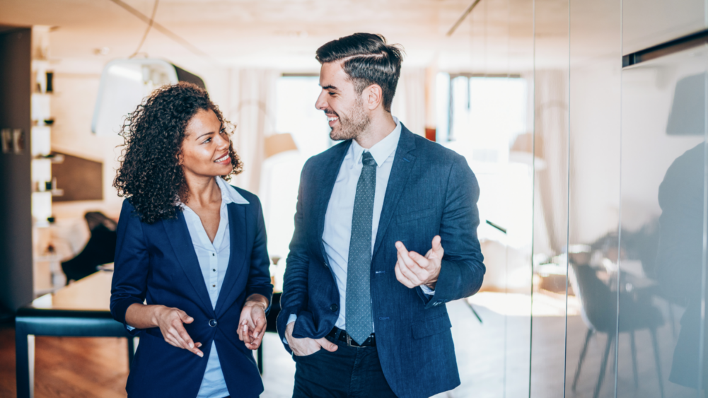 two employees smiling, walking and talking with each other
