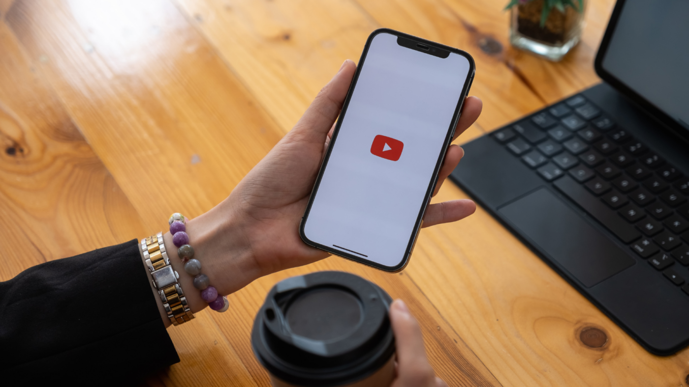 Woman holding phone with YouTube logo on it