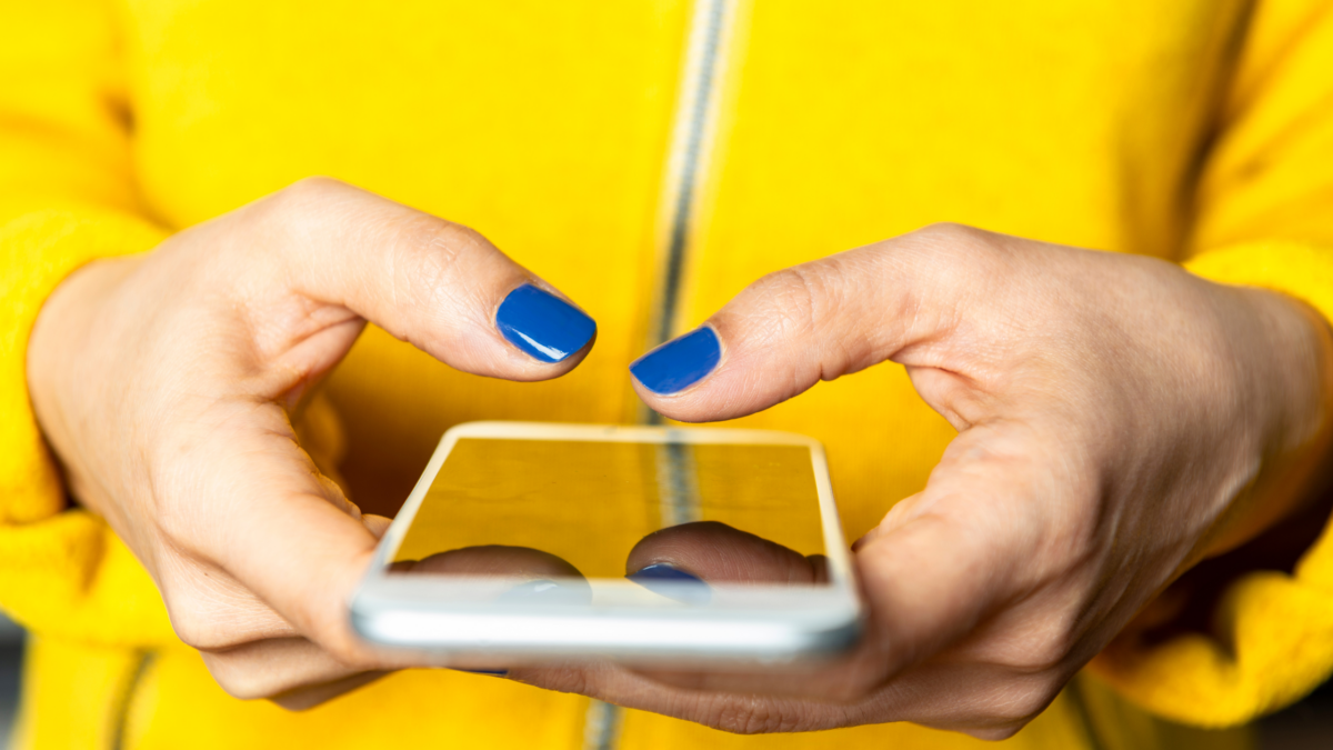 Woman with painted nails holding her phone and texting