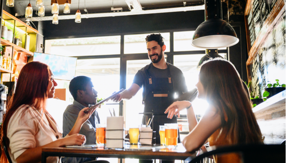 waiter at restaurant smiling and handing customer a menu